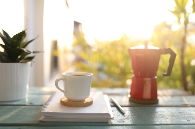Pote de café e moka e notebook na mesa de madeira azul ao ar livre