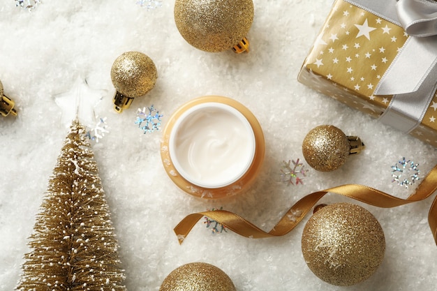 Pote de creme cosmético e acessórios de natal em fundo com neve decorativa