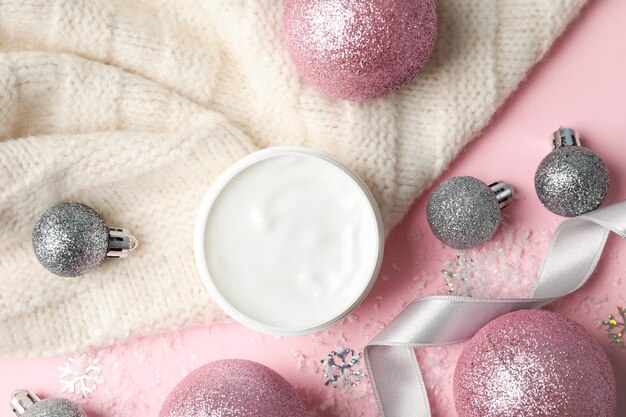 Pote de creme de inverno para a pele, blusa quente em rosa, espaço para texto. Vista do topo