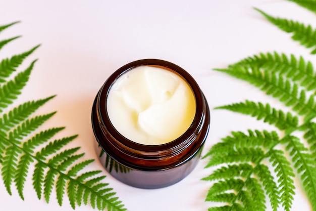 Foto pote de creme de rosto orgânico natural em folhas de samambaia. copie o espaço para o design da sua marca de cosméticos.