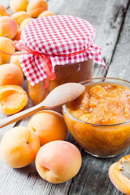 Pote de geléia e frutas frescas de damasco maduros na mesa