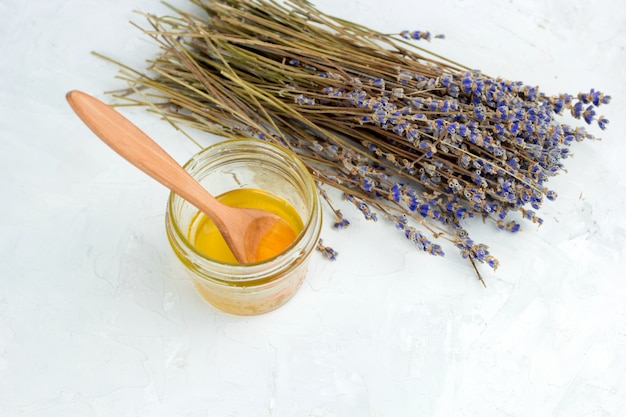 Pote de mel e flores de lavanda seca em um fundo de concreto gasto branco