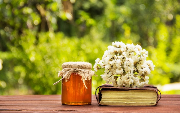 Pote de mel flor, livro velho e buquê de flores silvestres