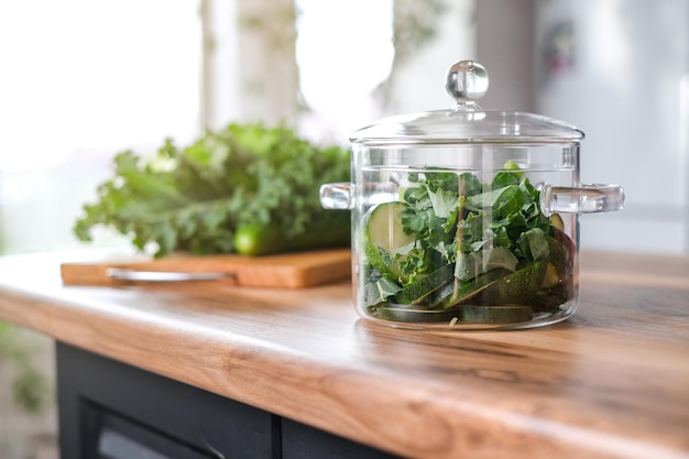 Pote de vidro elegante com legumes verdes na mesa da cozinha.