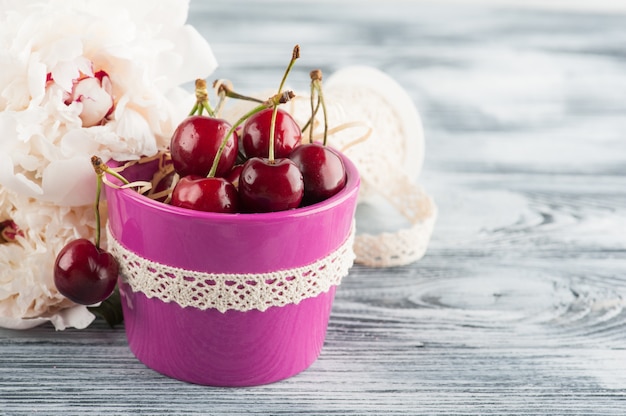 Pote roxo com cerejas e peônias.