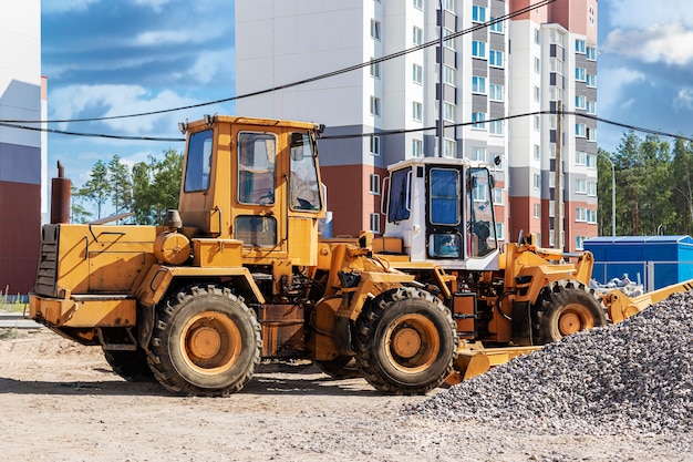 Potente cargador de ruedas para el transporte de mercancías voluminosas en el sitio de construcción de una moderna zona residencial. Equipo de construcción para elevación y movimiento de cargas.