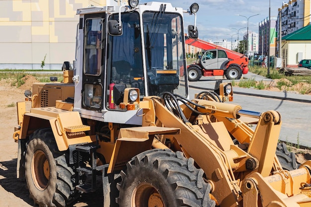 Potente cargador de ruedas para el transporte de mercancías voluminosas en el sitio de construcción de una zona residencial moderna. Equipo de construcción para elevación y movimiento de cargas.