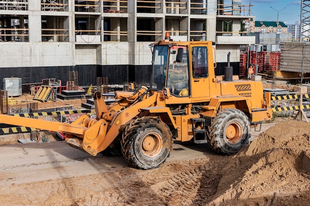 Potente cargador de ruedas para el transporte de mercancías voluminosas en el sitio de construcción de una zona residencial moderna. Equipo de construcción para elevación y movimiento de cargas.