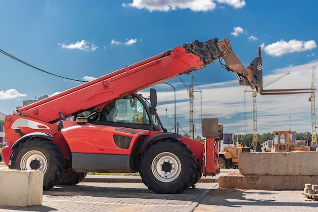 Foto potente carretilla elevadora de ruedas con mástil telescópico en el sitio de construcción de una moderna zona residencial. equipo de construcción para elevación y movimiento de cargas.