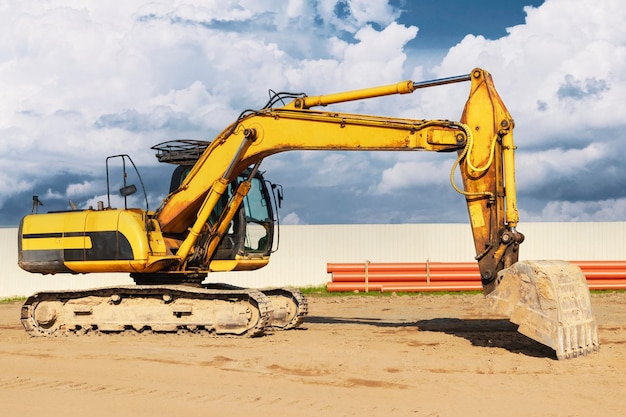 Potente excavadora en un sitio de construcción contra un cielo azul nublado Equipos de construcción de movimiento de tierras Máquinas de construcción modernas