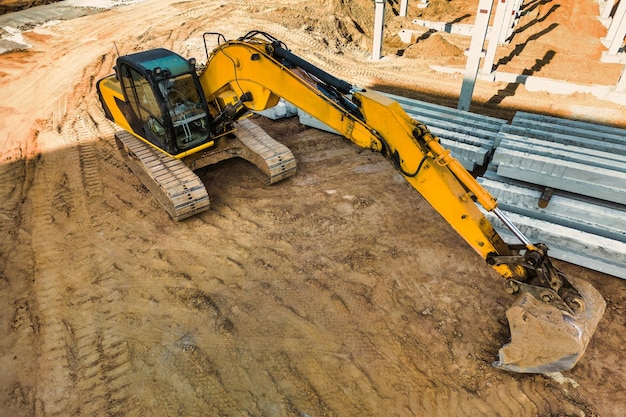 Una potente excavadora sobre orugas está trabajando en un sitio de construcción Vista de cierre desde arriba Preparación de un pozo para la construcción Excavación