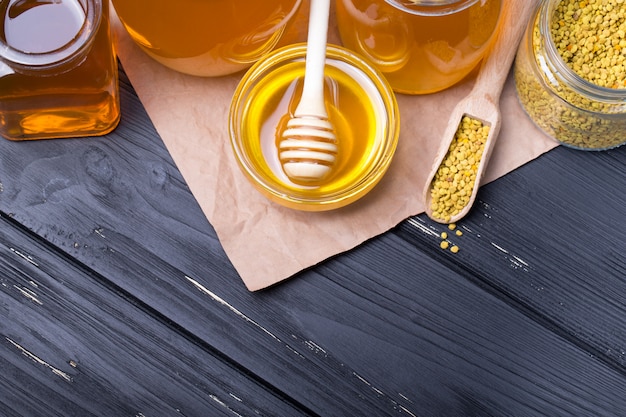 potes de mel com pau na mesa de madeira