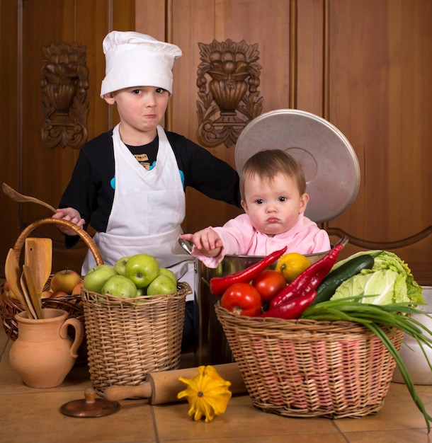 Potes y verduras para niños Retrato de un bebé sonriente sentado dentro de una olla grande rodeada de verduras y comida