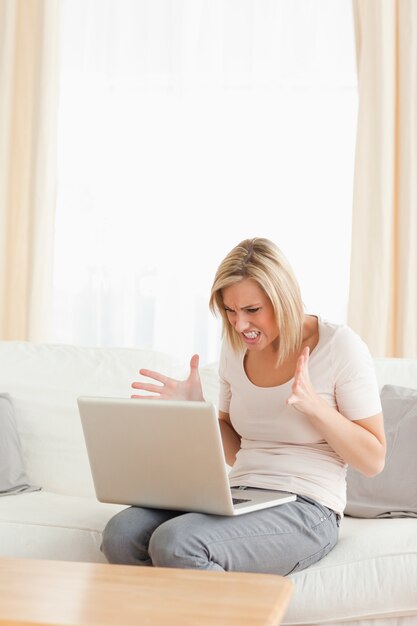 Potrait de una mujer rubia molesta usando una computadora portátil