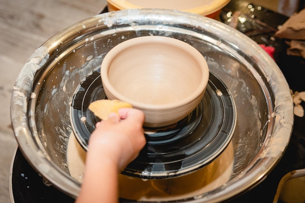 Potter arbeitet an der Töpferscheibe mit Ton Verfahren zur Herstellung von Keramikgeschirr in der Töpferwerkstatt Handwerks- und Kunstkonzept