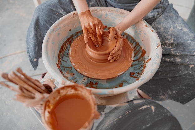 Potter crea cuenco en rueda de alfarero en el interior