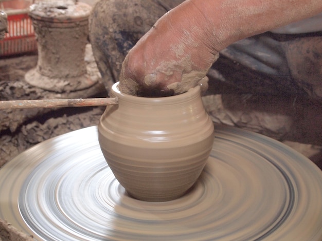 Potter hace en la olla de barro la rueda de alfarería.