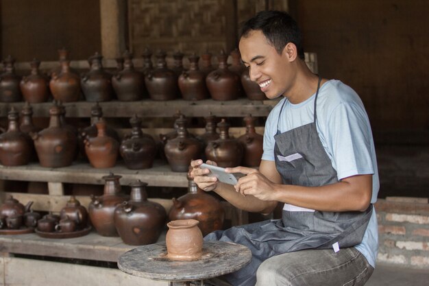 Potter hombre tomando foto de su producto en el taller de cerámica