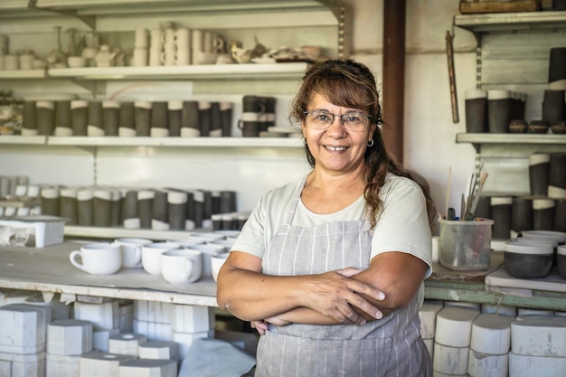 Potter mujer adulta sonriendo y mirando a la cámara en su estudio