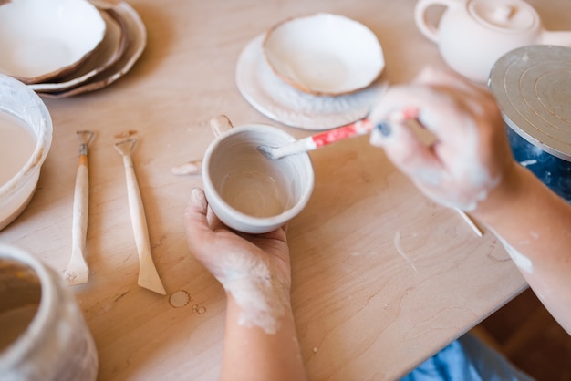 Potter mujer con pincel pinta una olla