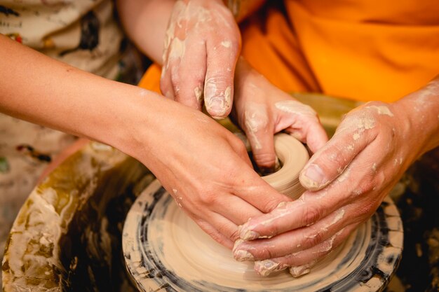 Potter trabalhando na roda de oleiro com argila. Processo de fabricação de louças de cerâmica na oficina de cerâmica. Conceito de artesanato e arte.