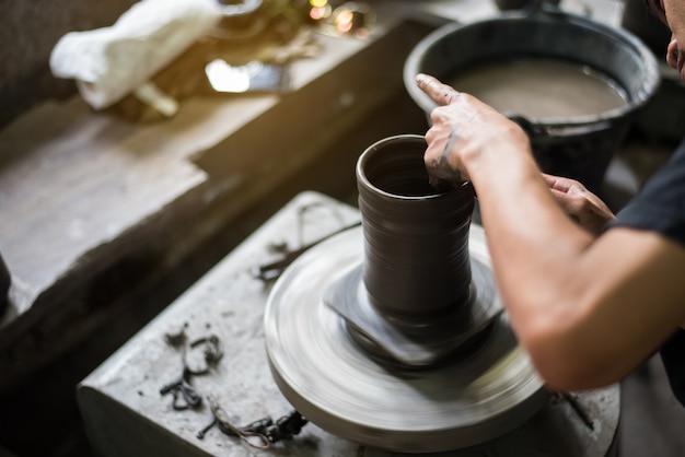 Potters Hände formen weichen Ton zu einem irdenen Topf