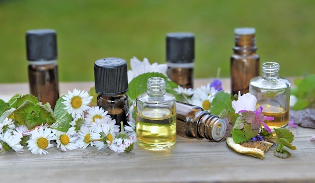 Poucas garrafas de óleo essencial com flores sobre uma mesa sobre fundo verde