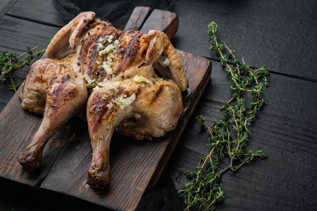 Poussin de espatchcock asado, sobre mesa de madera negra