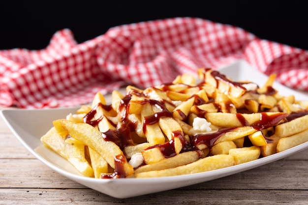 Poutine canadiense tradicional sobre mesa de madera