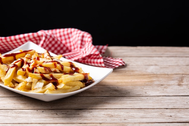 Poutine canadiense tradicional sobre mesa de madera