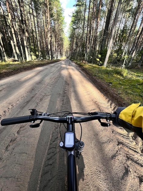 POV de andar en bicicleta Primer plano del manillar de la bicicleta con fondo de camino de ripio forestal