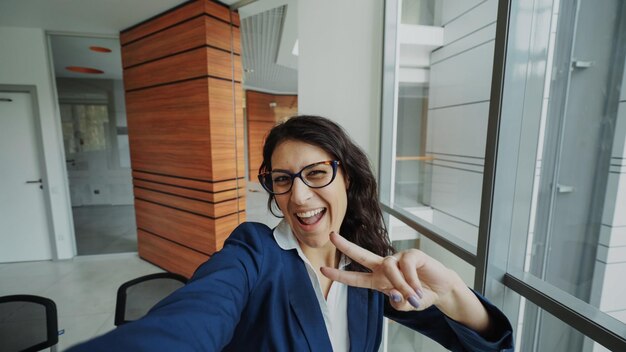 POV da jovem empresária de terno tirando uma foto selfie segurando o smartphone e se divertindo