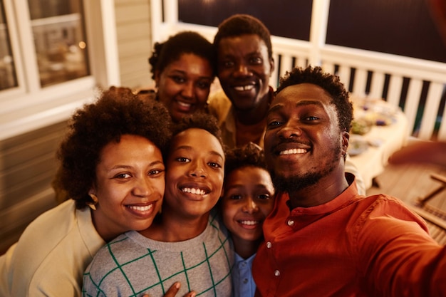 Pov de família afro-americana feliz tirando foto de selfie no terraço da casa à noite