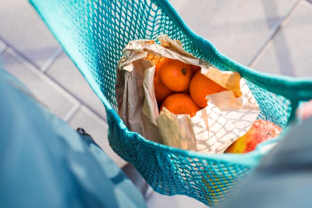 POV muchas naranjas en bolsas de papel dentro de una bolsa de compras de malla hecha a mano azul Primer plano desde arriba ver frutas en una bolsa