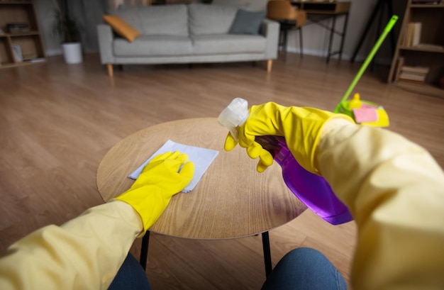 Foto pov de mujer mesa de limpieza con trapo rociando detergente en interiores