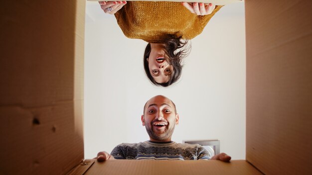 Foto pov de pareja festiva abriendo la caja presente sintiéndose alegre