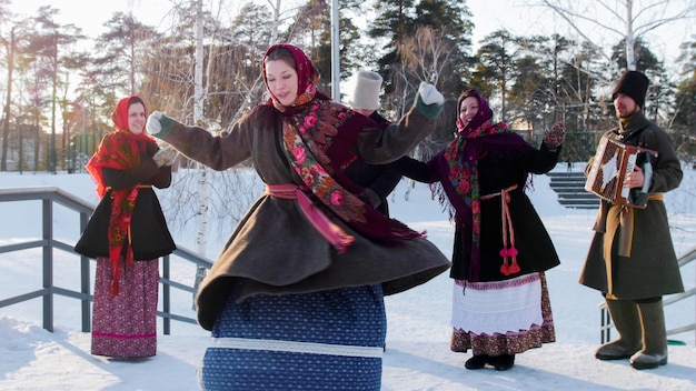 Povo do folclore russo em botas de feltro dançando ao ar livre no inverno