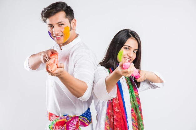 Povo indiano celebrando o holi com doce laddu, cores em thali e respingos de cores