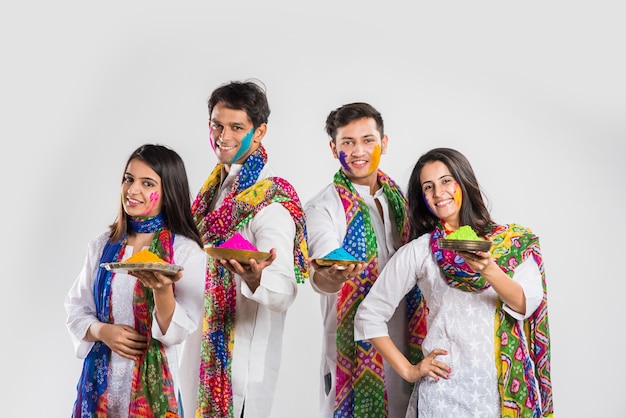 Povo indiano celebrando o holi com doce laddu, cores em thali e respingos de cores