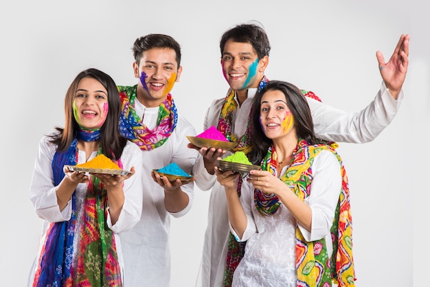 Povo indiano celebrando o holi com doce laddu, cores em thali e respingos de cores
