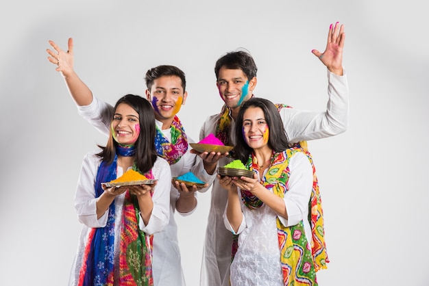 Povo indiano celebrando o holi com doce laddu, cores em thali e respingos de cores