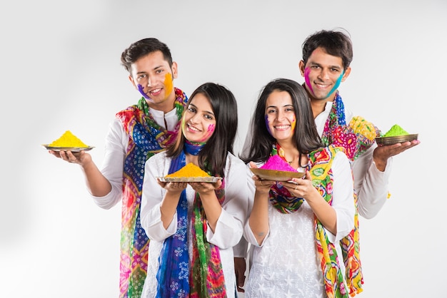 Povo indiano celebrando o holi com doce laddu, cores em thali e respingos de cores