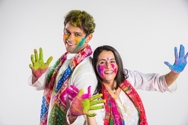 Povo indiano celebrando o holi com doce laddu, cores em thali e respingos de cores