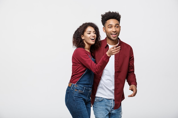 Povos afro-americanos novos na roupa ocasional que olham afastado e apontam o dedo.