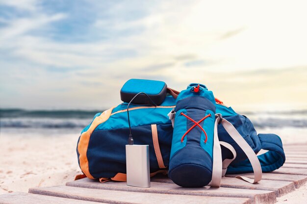 Power Bank carga un altavoz musical en un contexto de bolsas de viaje en la playa en un día nublado