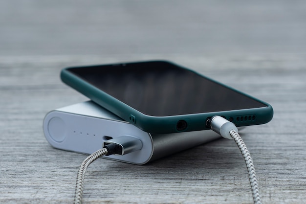 Power Bank carrega um smartphone em um banco de madeira no parque.