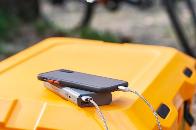 Powerbank carga un teléfono inteligente en un refrigerador turístico en el contexto de una bicicleta en la naturaleza Concepto sobre el tema del turismo y los viajes