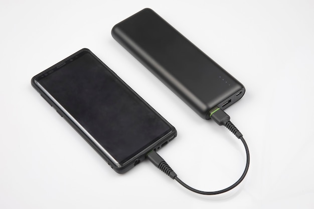 Powerbank carrega uma bateria de smartphone em um fundo branco. tecnologias e dispositivos digitais