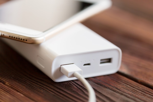 Powerbank y celular en mesa de madera.