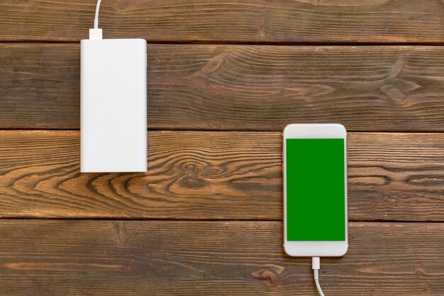 Powerbank e celular na mesa de madeira